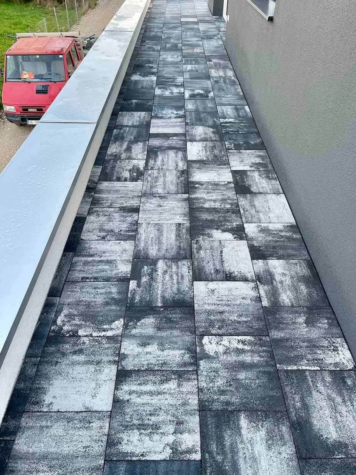 Narrow paved passage between a rendered wall and a low parapet.