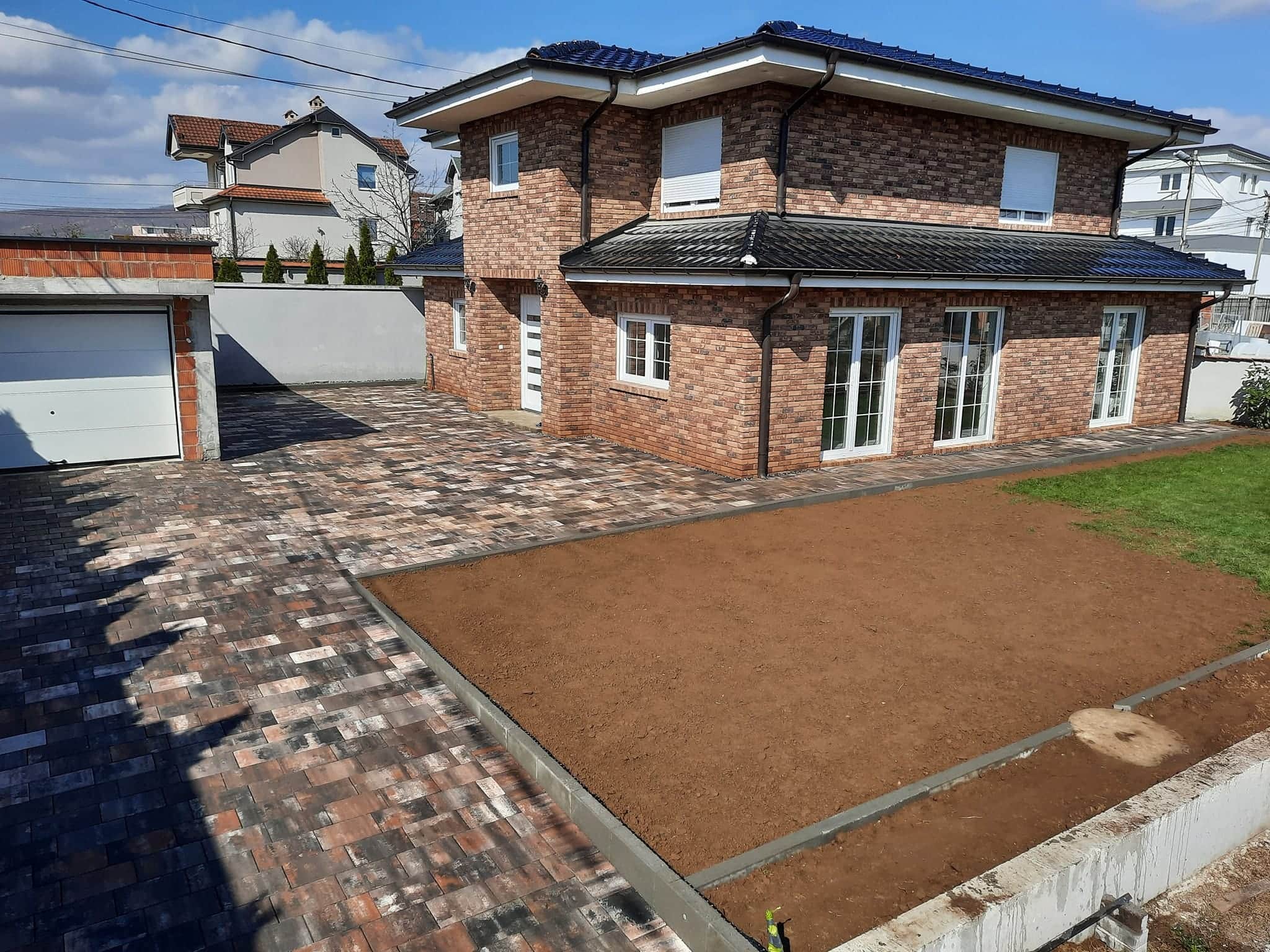 The house's garage with paved forecourt and a rectangular panel of worked earth.
