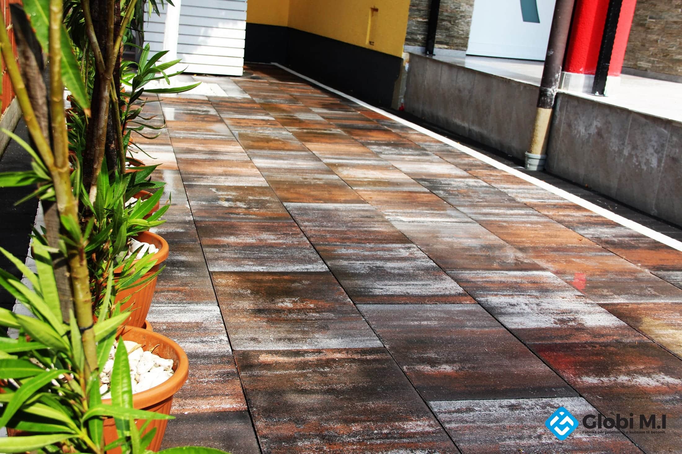 Narrow paved strip beside the house, with potted plants along it.