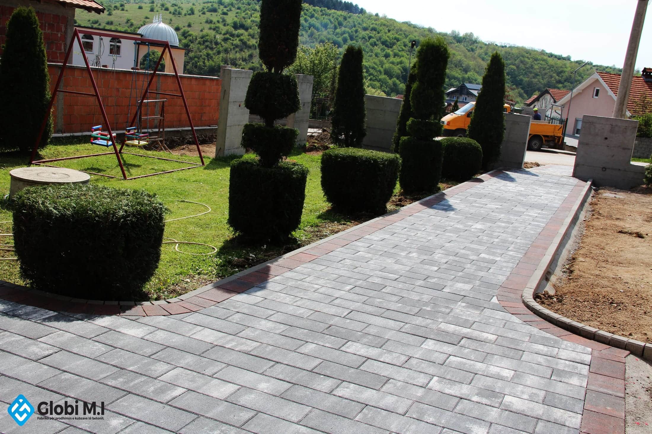 Clipped shrubs along a paved driveway.