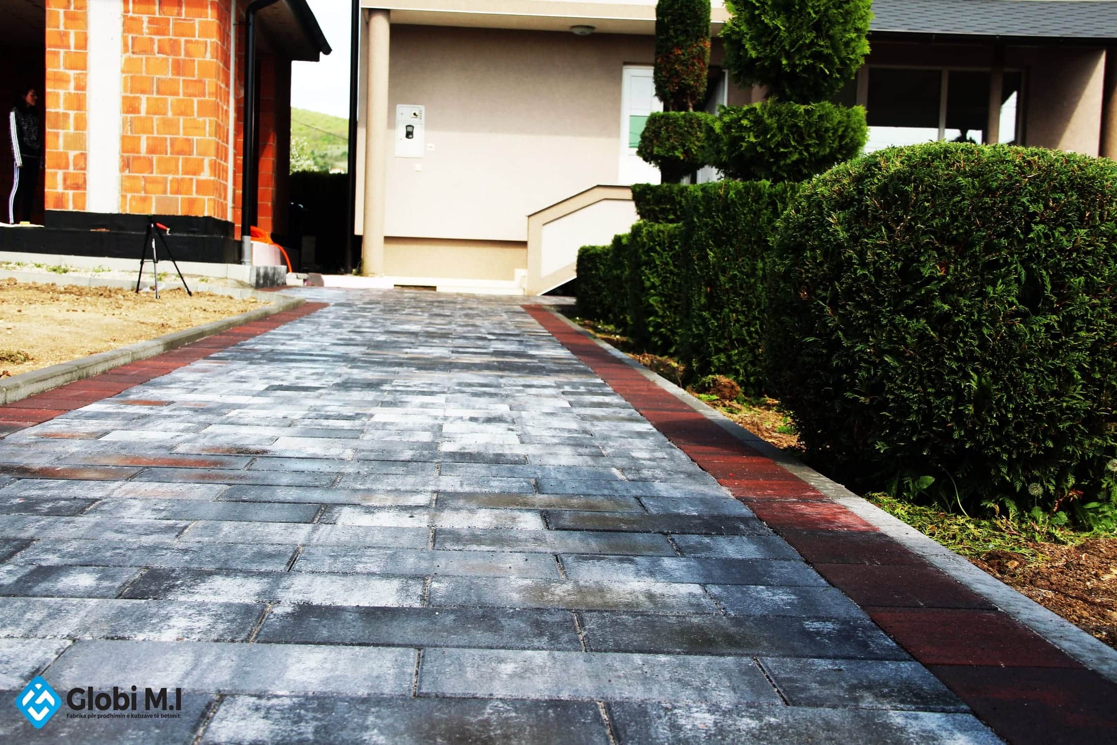 Paved driveway between clipped shrubs, leading to a garage.