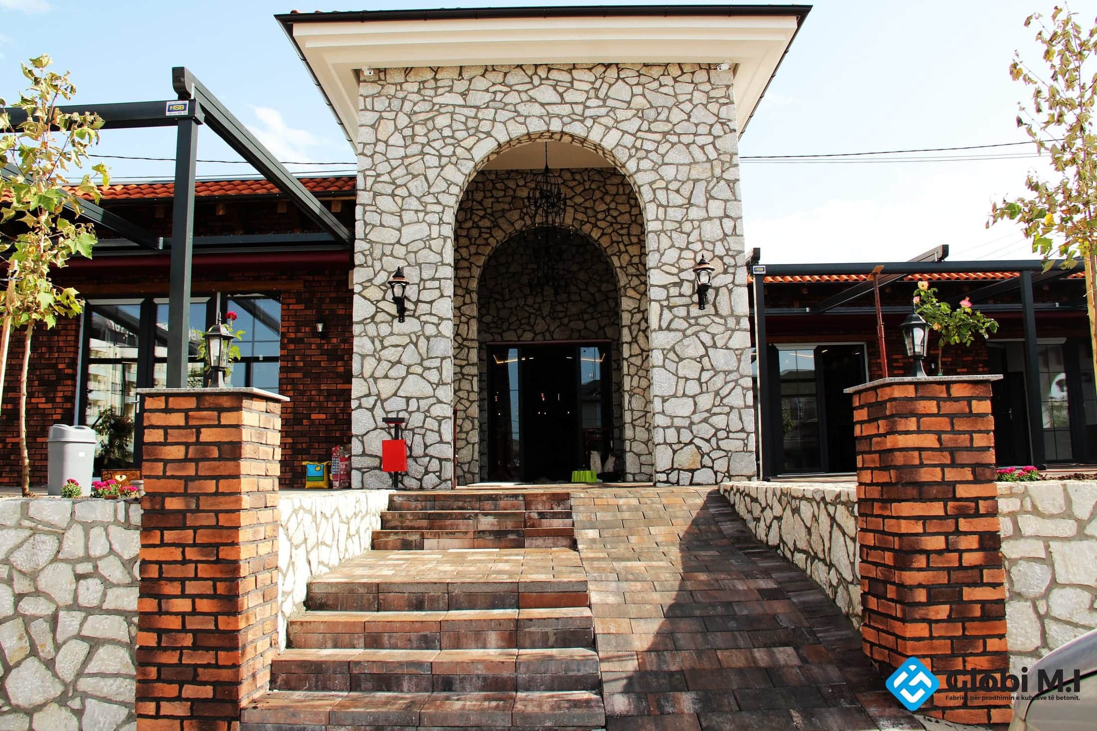 Stone-faced arched entrance with brick piers and steps rising from the paving.