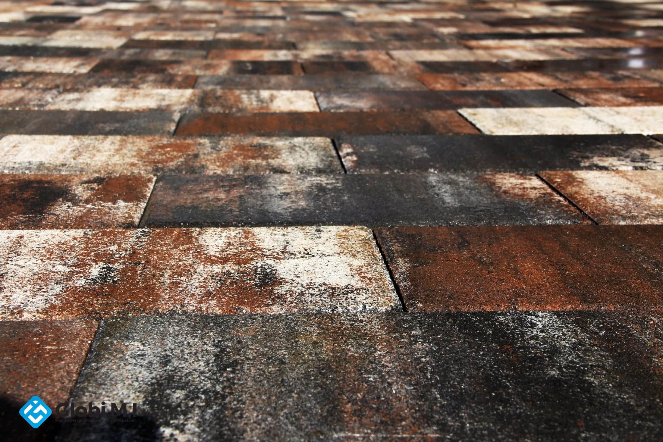 Wide paved area in sun and shade, slabs in mixed rust tones.