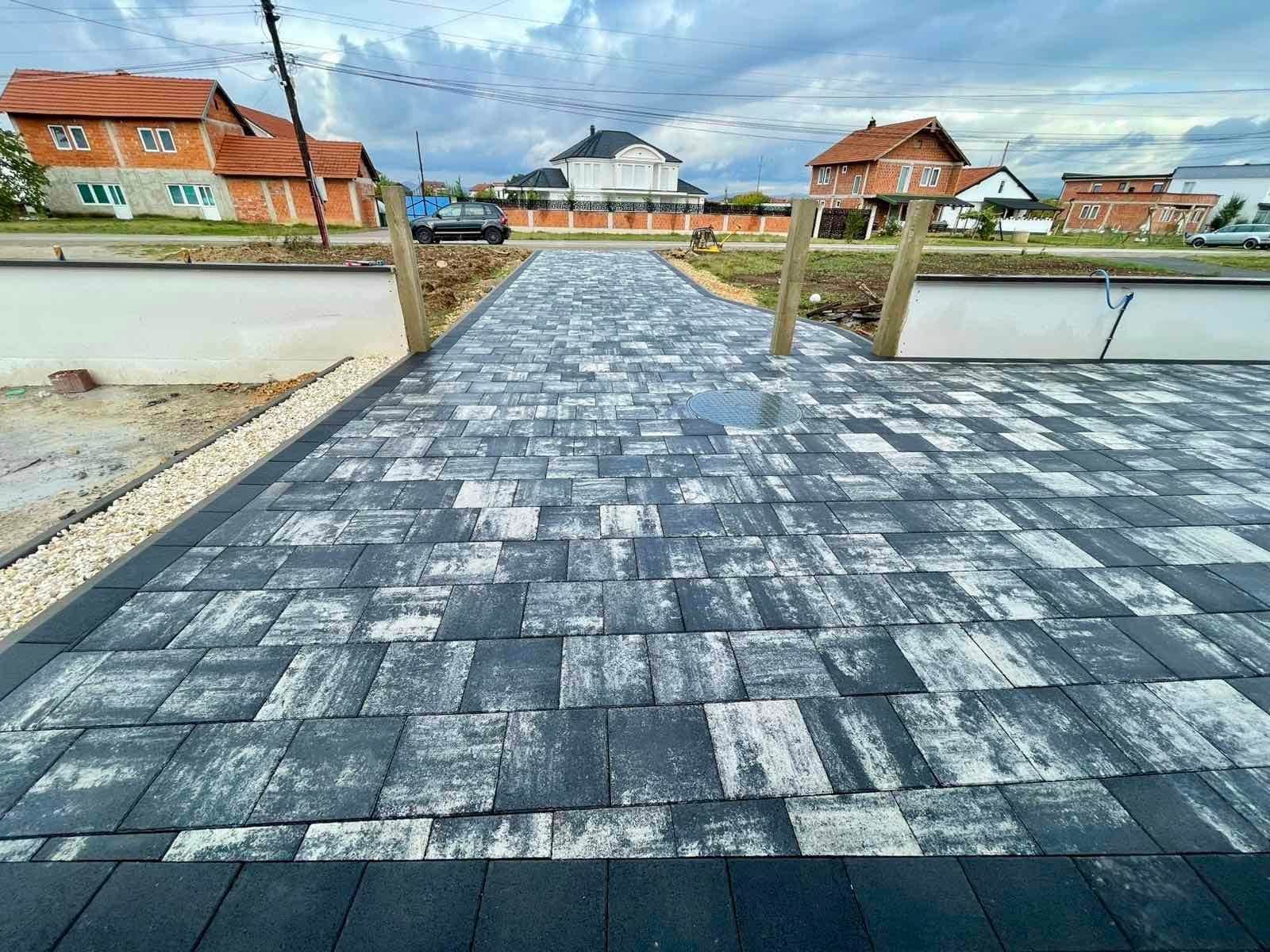 Paved driveway seen from the street, with neighbouring houses.