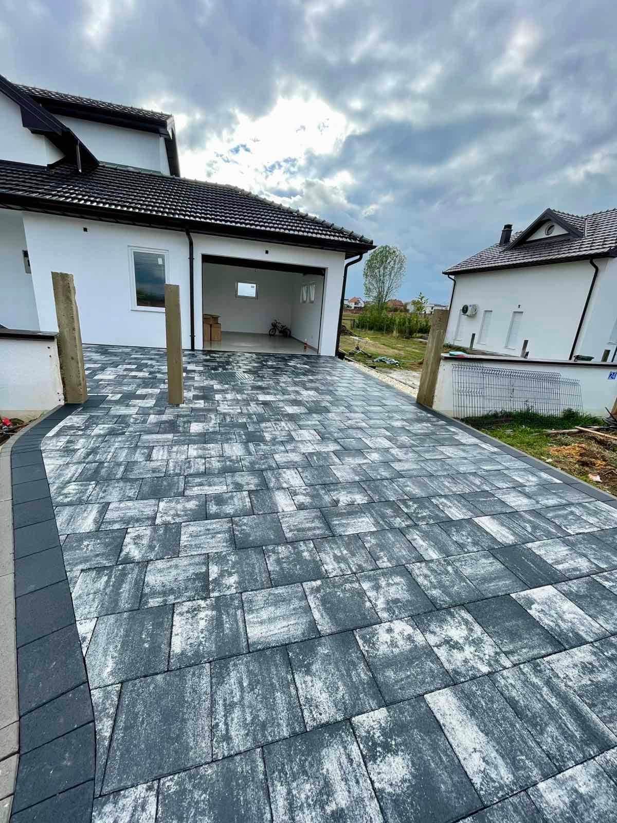 Paved area in front of a garage, with timber posts.