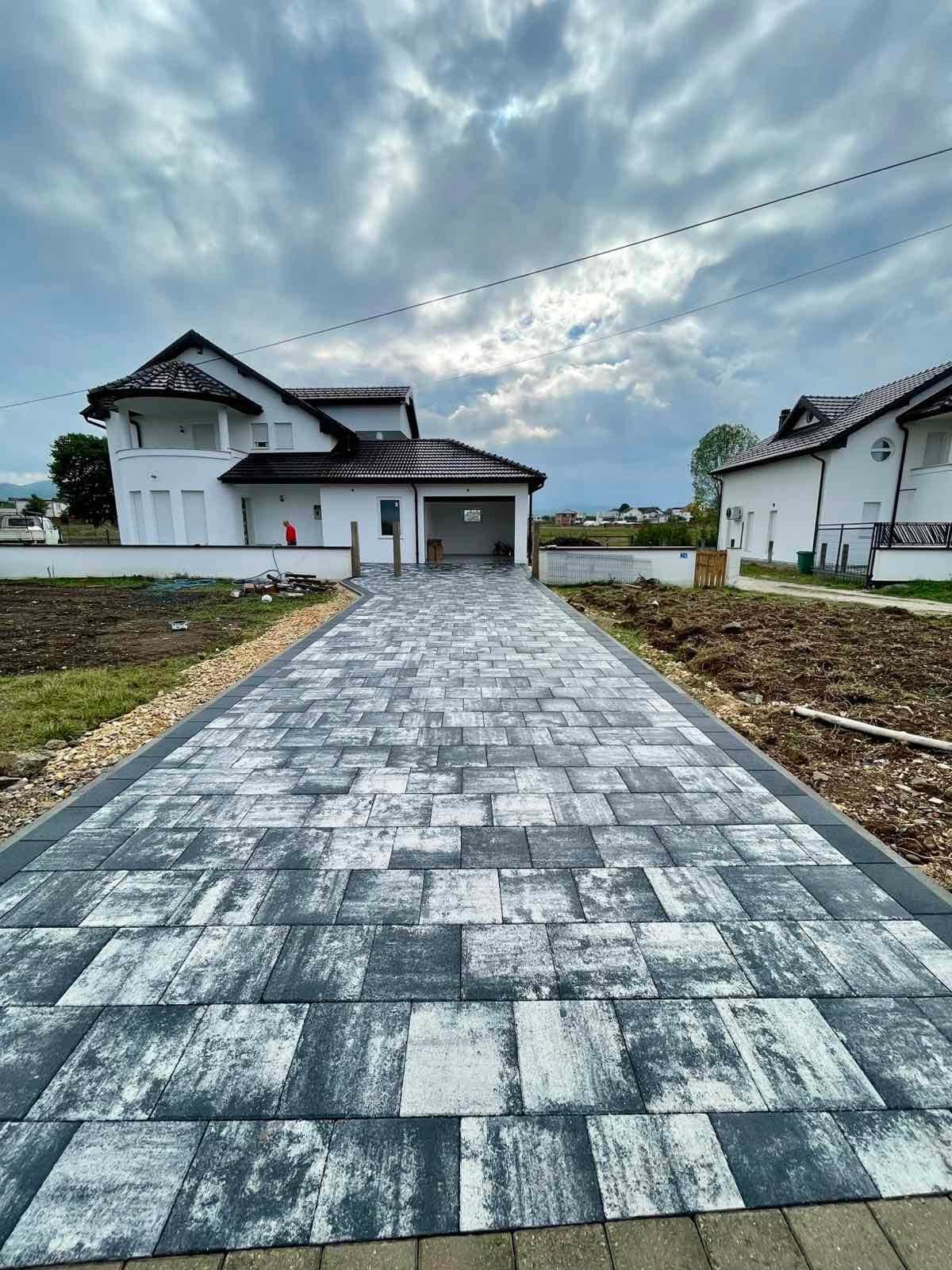 Private house with a paved driveway and unfinished ground alongside.