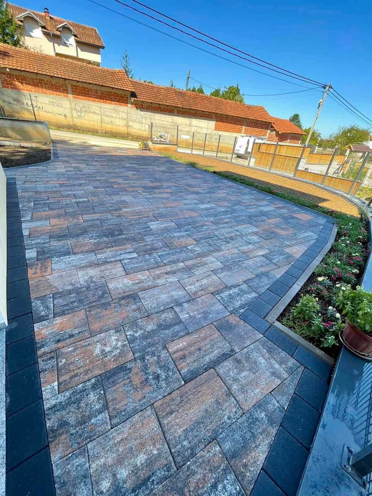 Wide paved forecourt curving round, edged with a dark border course.