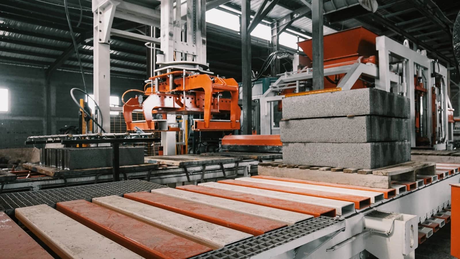 Concrete blocks stacked on a wooden pallet on the Globi MI production line, with the press machinery behind them