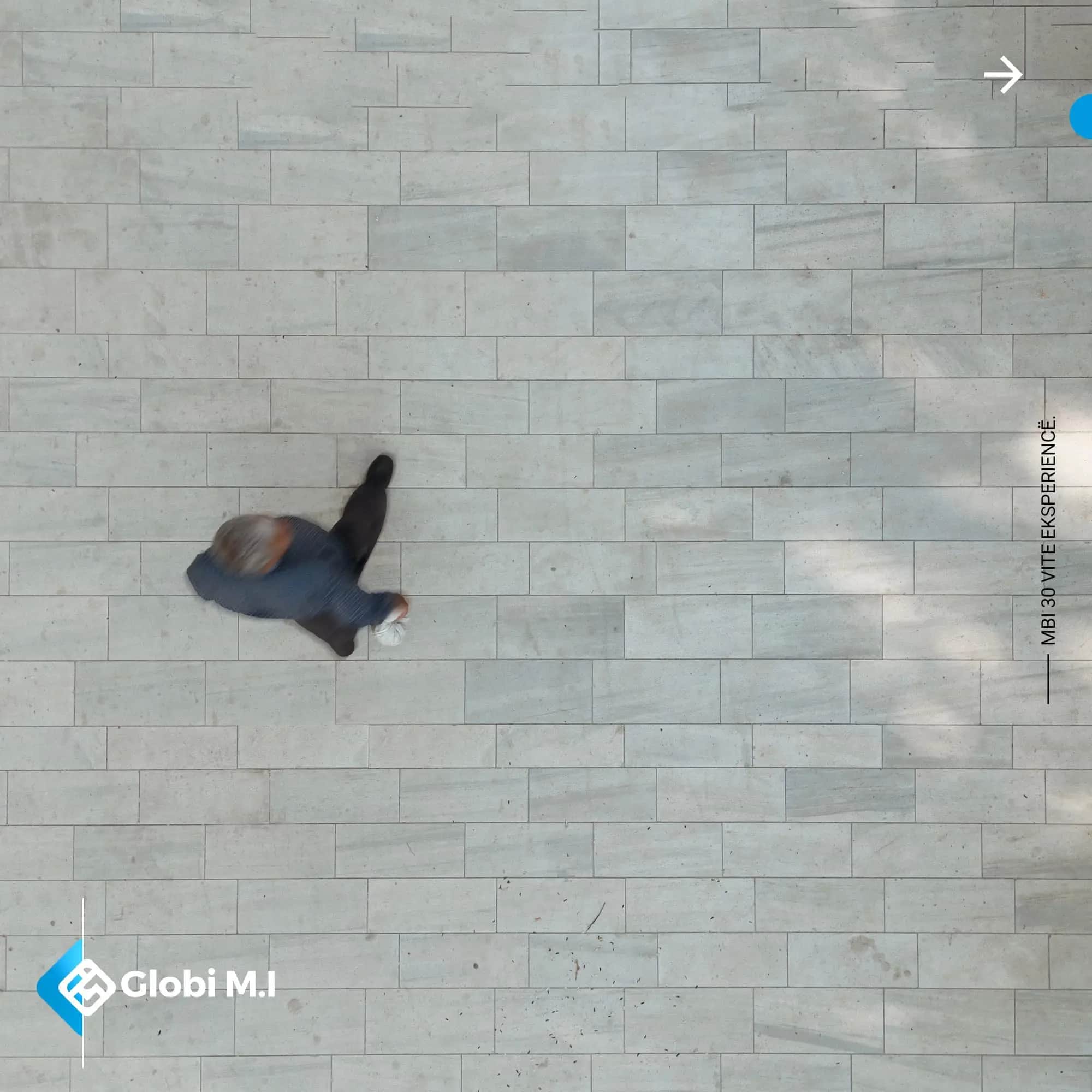 The paved surface of Kamenicë Boulevard seen straight down, with one person walking.